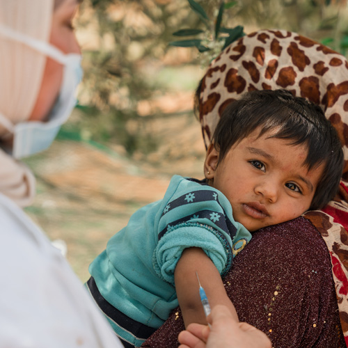 En gutt blir holdt av mamma mens han får satt meslingvaksine, Jordan