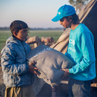 En UNICEF-ansatt gir et teppe til en gutt i Pakistan
